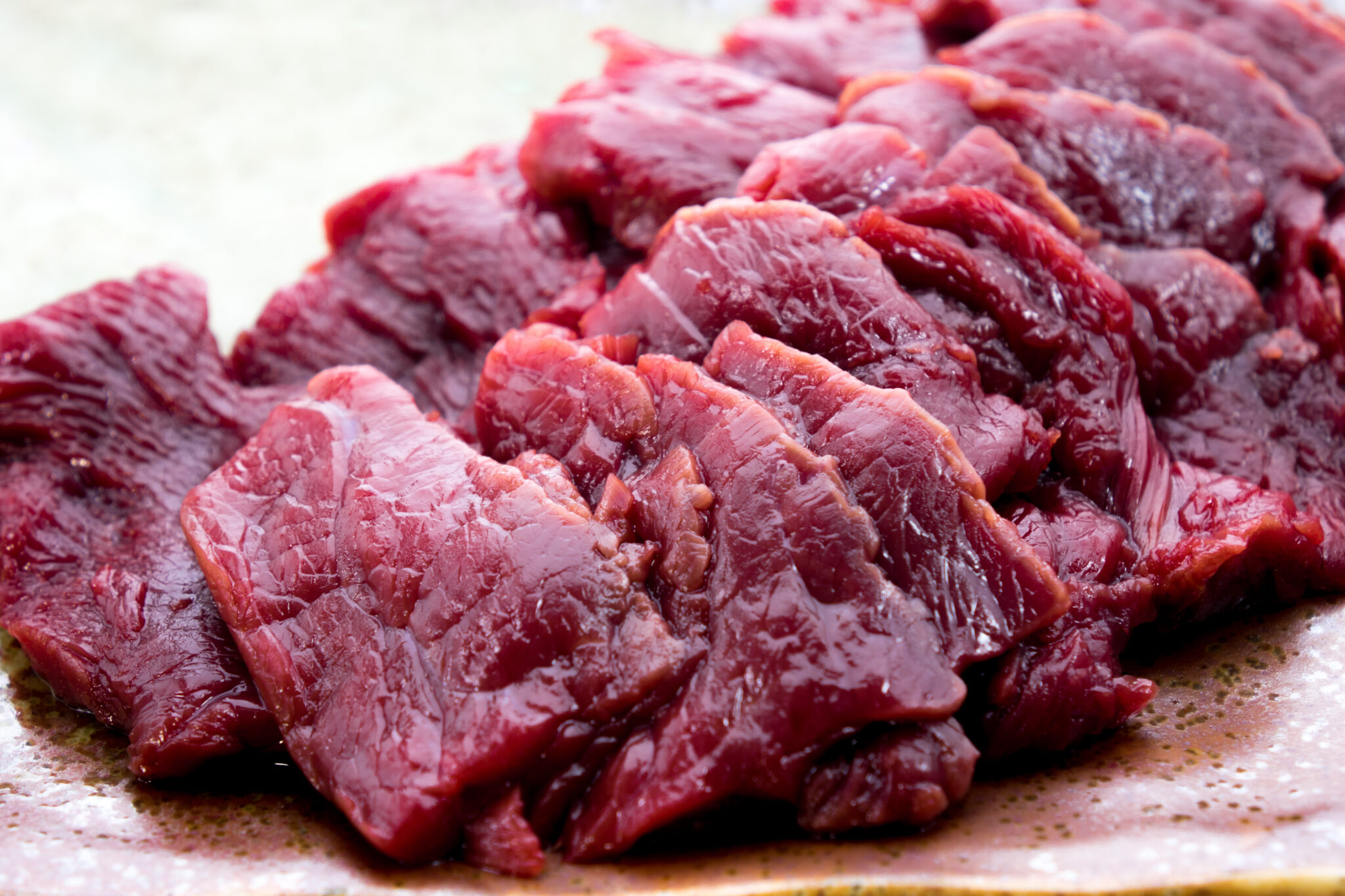 皿に重ねて並べた、深い赤色の馬刺しヒレ肉のスライス