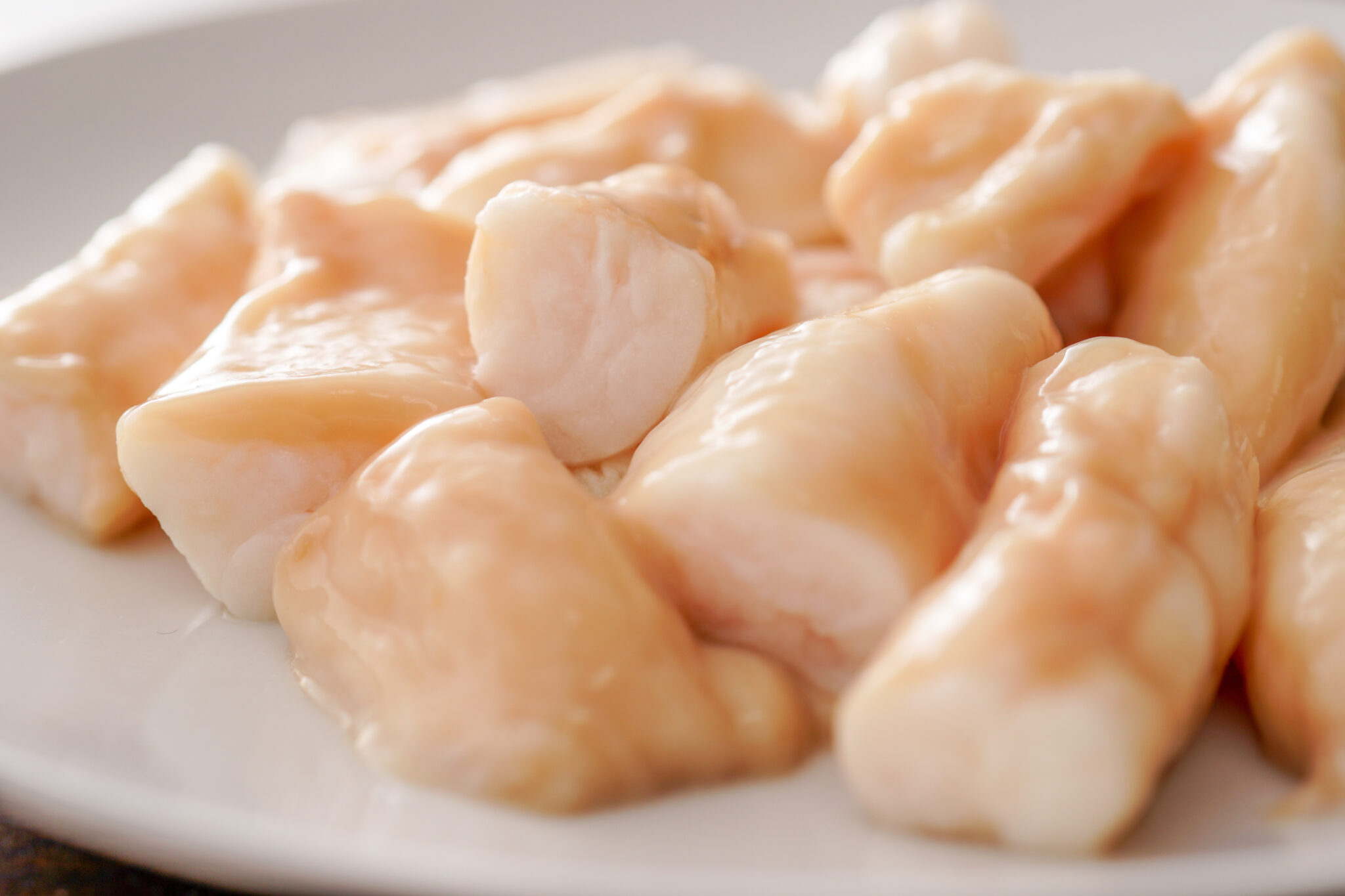 食品イメージ:白い皿に盛り付けた下処理済みの丸腸。乳白色でつやのある生の状態のクローズアップ
