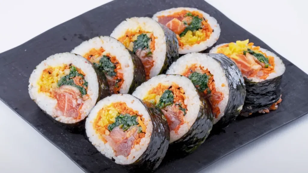 カットされたキンパを黒い皿に並べた画像|彩り豊かな具材が入った韓国風のり巻き