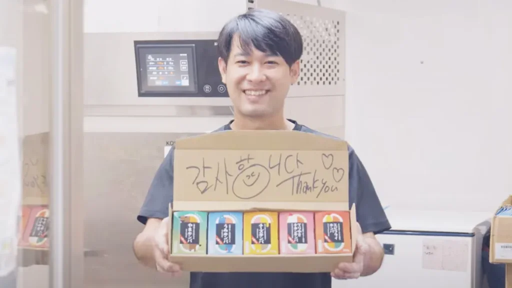 アゴラキッチン代表がキンパ詰め合わせを持って笑顔で立つ姿｜3Dフリーザー導入店舗インタビュー