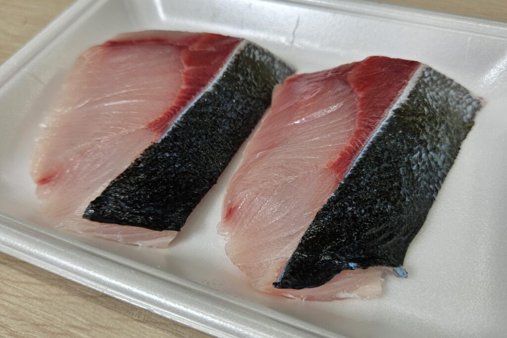 発泡トレーに並べられたブリの切り身二切れ｜鮮度の高い生魚の断面写真