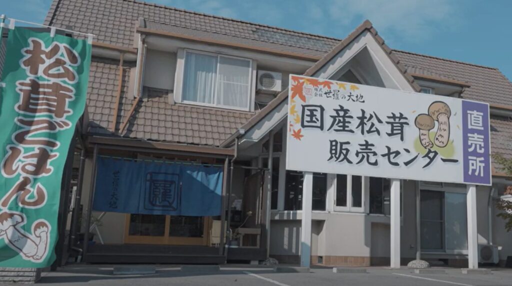 世羅の大地の外観　国産松茸販売センター直売所の看板と松茸ご飯ののぼり旗が立つ店先の写真