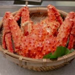 氷の上に竹籠で盛り付けられた茹でたてのタラバガニ｜新鮮で高級感のある海鮮イメージ