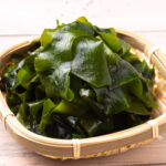 竹籠に盛られた鮮やかな緑色のボイルわかめ｜新鮮で栄養豊富な海藻