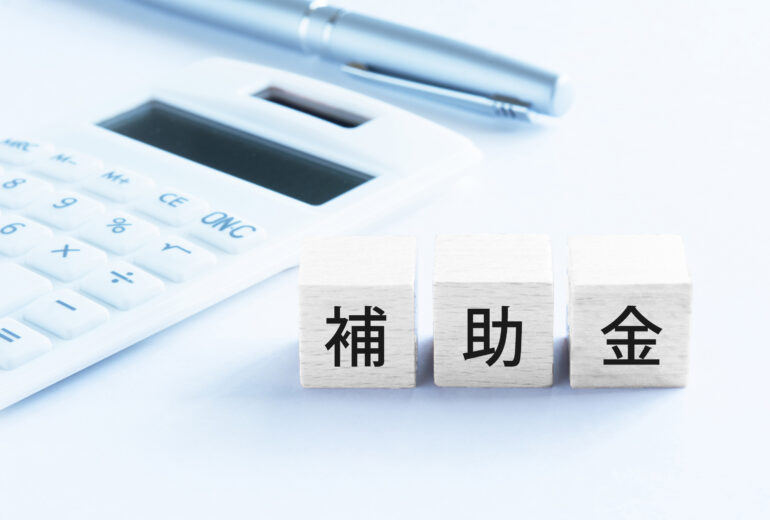 補助金を活用した設備導入や省エネ対策をイメージした写真｜電卓とペンと補助金の文字ブロック