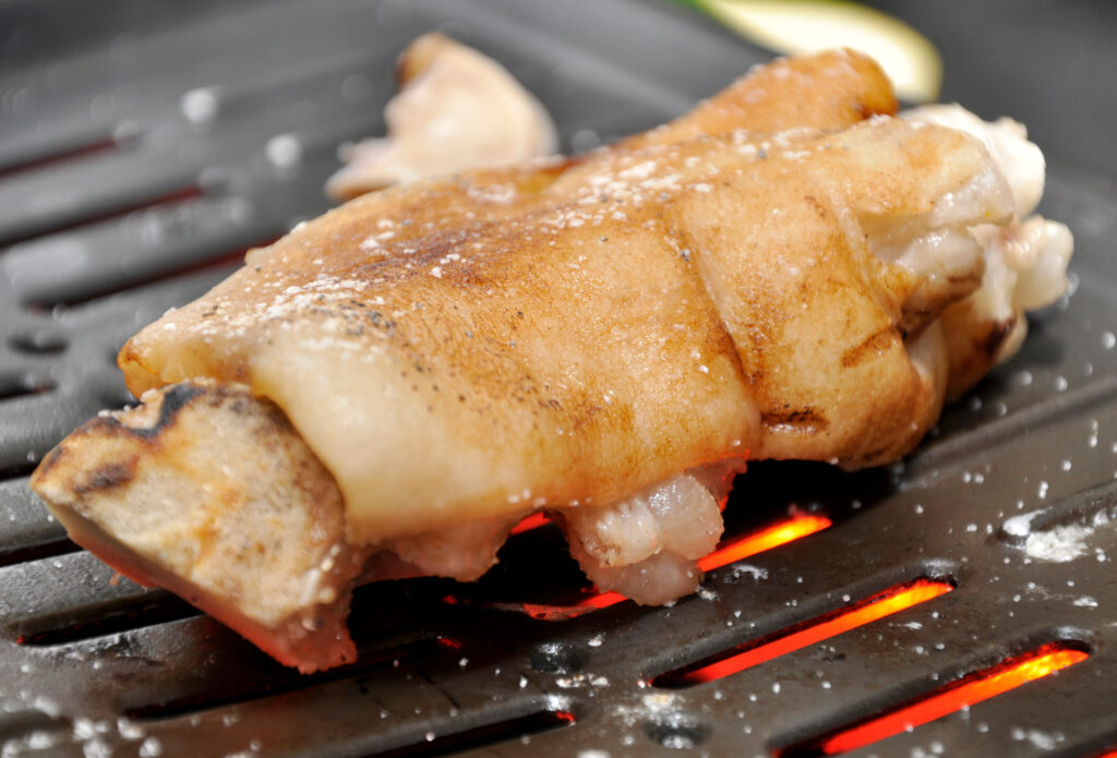 網の上で豚足が焼かれている