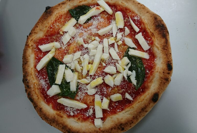 トレーにのせられた焼成前のピザ