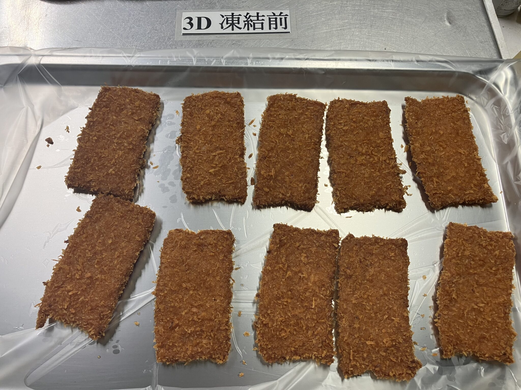 「3D 凍結前」の表示があるアルミトレーに、茶褐色の長方形のフィッシュカツ10枚を間隔を空けて並べた写真