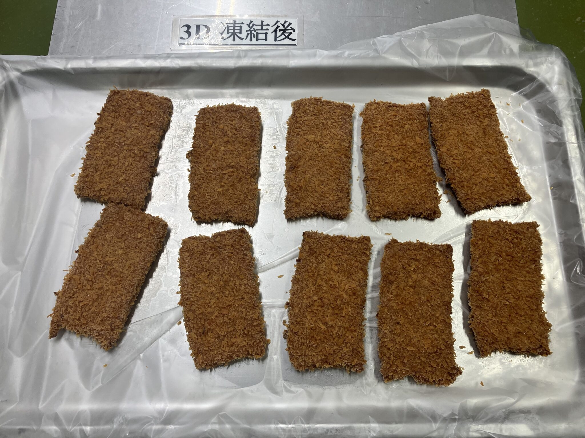 「3D 凍結後」の表示があるアルミトレーに、茶褐色の長方形のフィッシュカツ10枚を並べた凍結後の写真