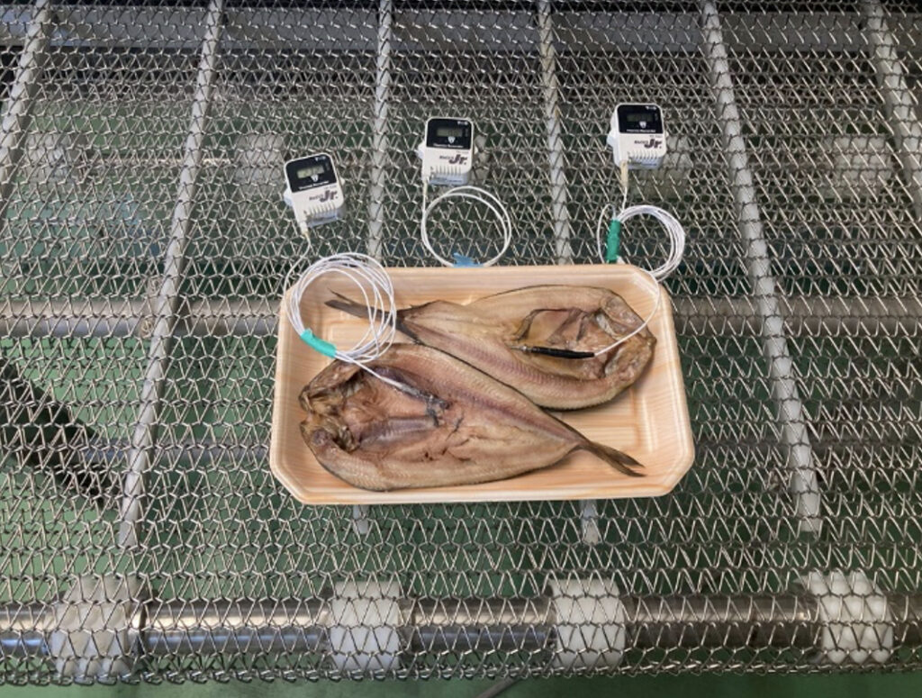 トンネルフリーザーのベルトに載せられたトレイ入りのほっけ（冷凍前）