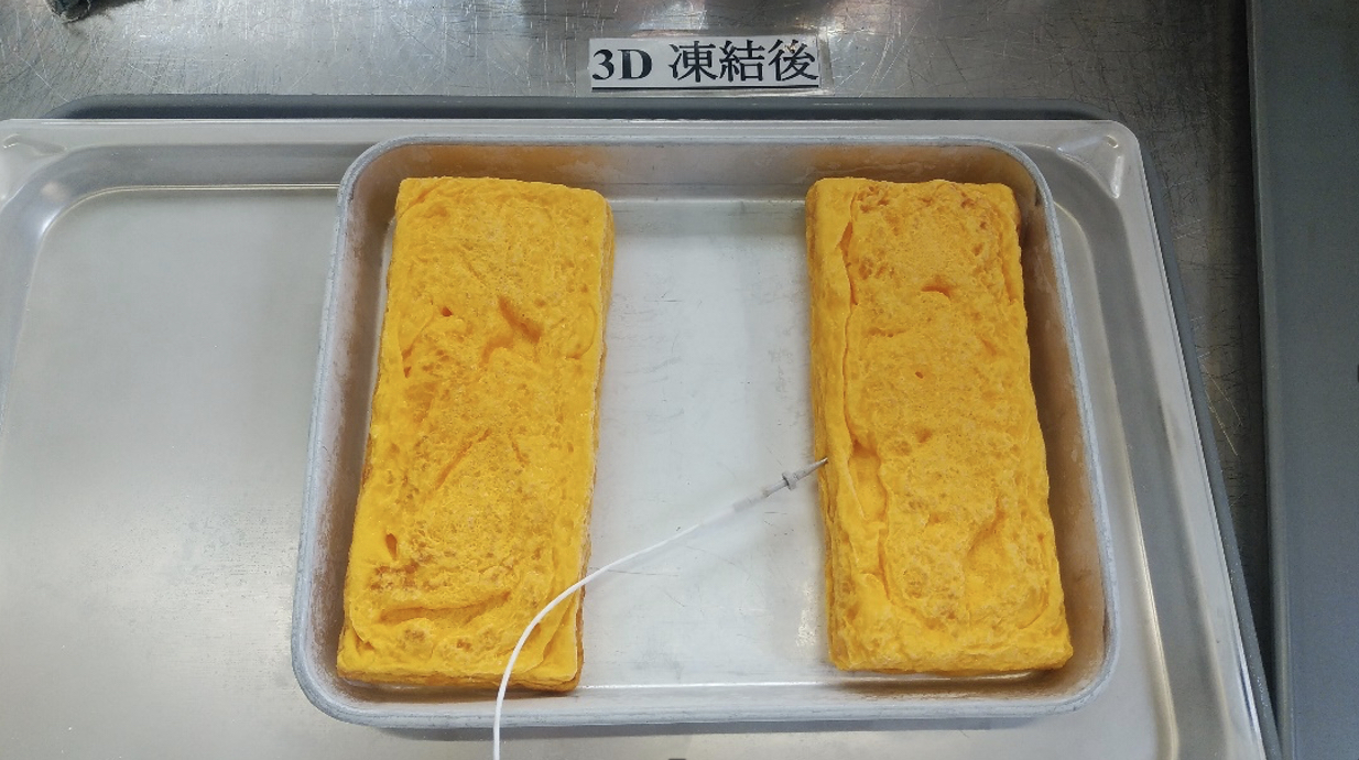 「3D 凍結後」の札の下、アルミトレーに並ぶ厚焼き玉子2本と、右の玉子へ差し込まれた白い温度センサー