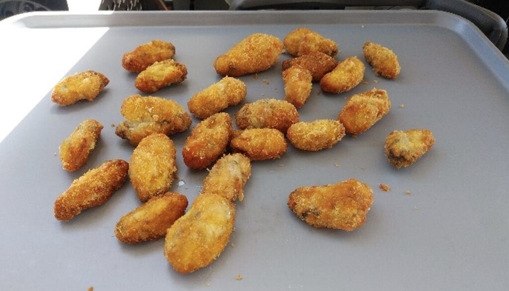 トレーに並べられた揚げたての牡蠣フライ