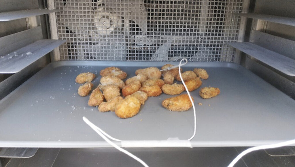 トレーに並べられた揚げたての牡蠣フライを急速冷凍中