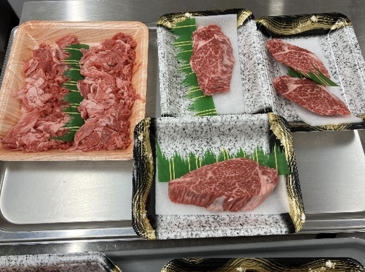 ステンレス台の4枚のトレーに、細かな牛肉と霜降りの厚切り牛ステーキを規格別に並べた写真