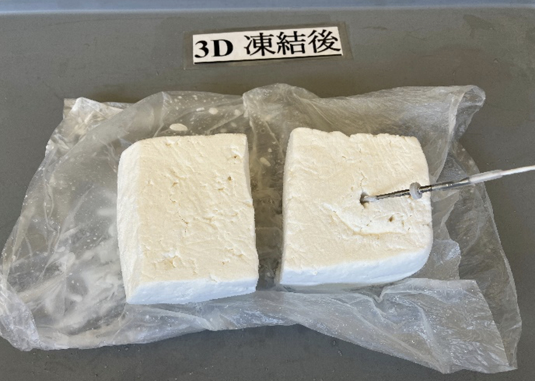 灰色のトレー上に並ぶ白い角形チーズ2個と、右側のチーズに差し込まれた中心温度計の「3D 凍結後」写真