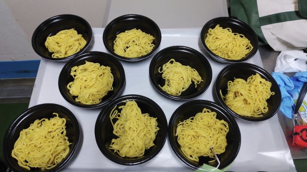 トレーに並べられた容器に入ったたくさんの中華麺