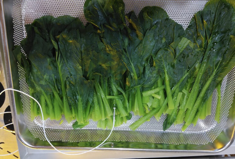 トレーに盛り付けられたボイル後のほうれん草