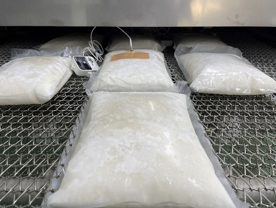 トンネルフリーザーから急速冷凍された大根おろしパックが出てくる様子