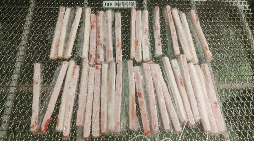 コンベアに載せられた急速冷凍されたかにかま