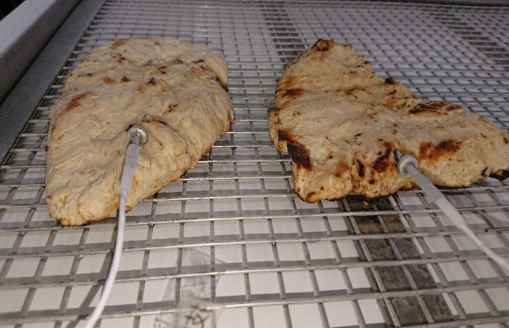 急速冷凍された網トレーに乗った2個のローストチキン