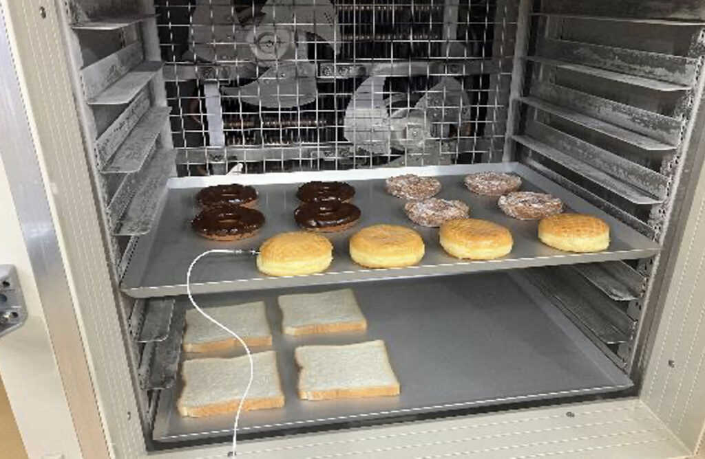 トレーにのせられた冷凍前のドーナツが急速冷凍されているところ