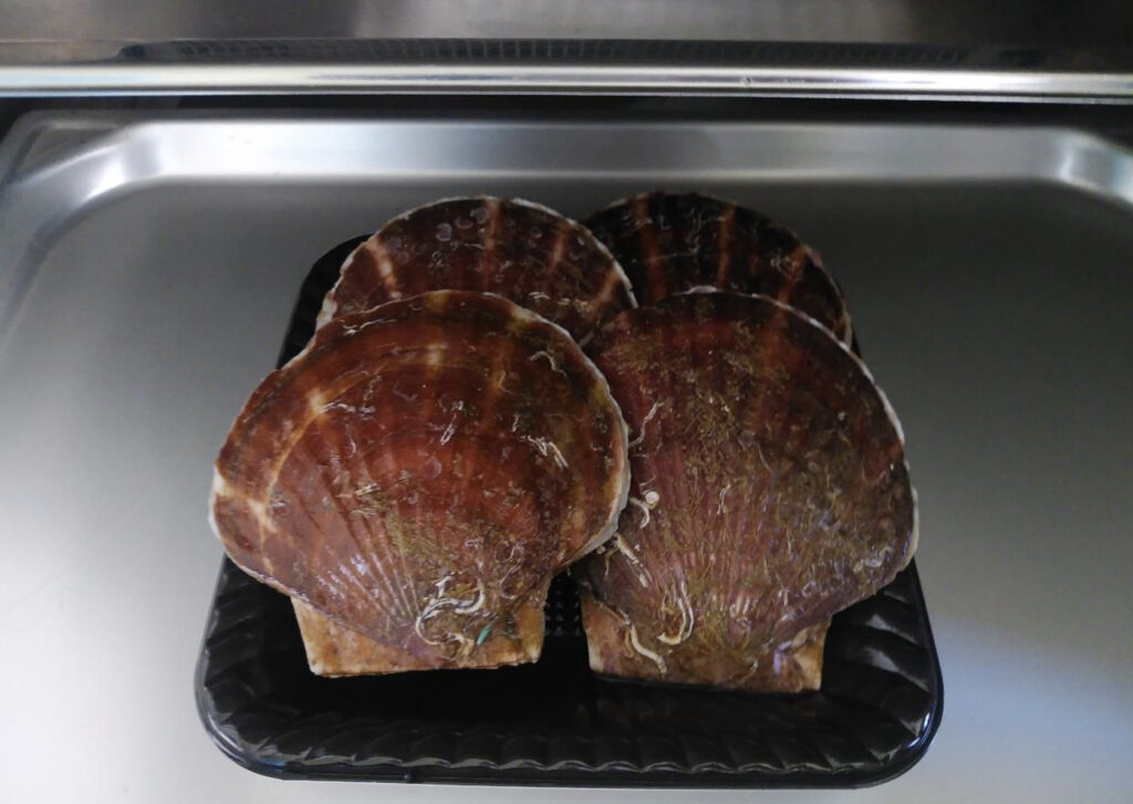 トレーの上にのせられたホタテ殻つき