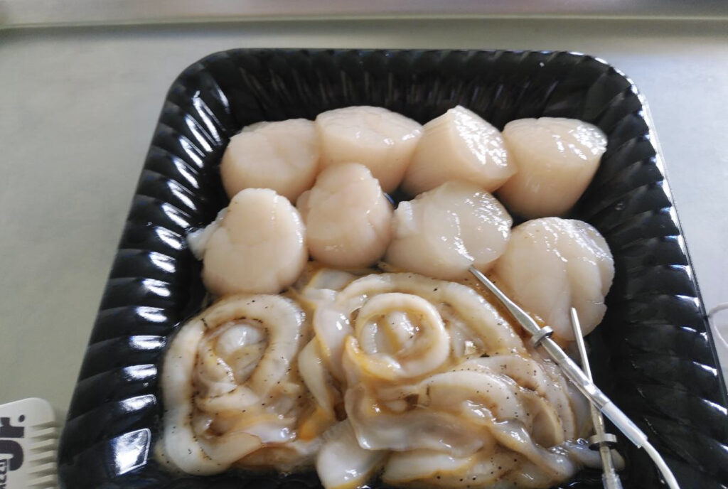 黒いトレイの中に入った生ホタテ