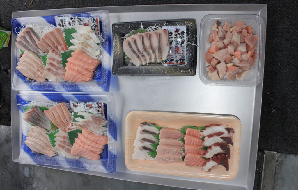 トレーの上にたくさんの急速冷凍された刺身のトレーパックがのっている