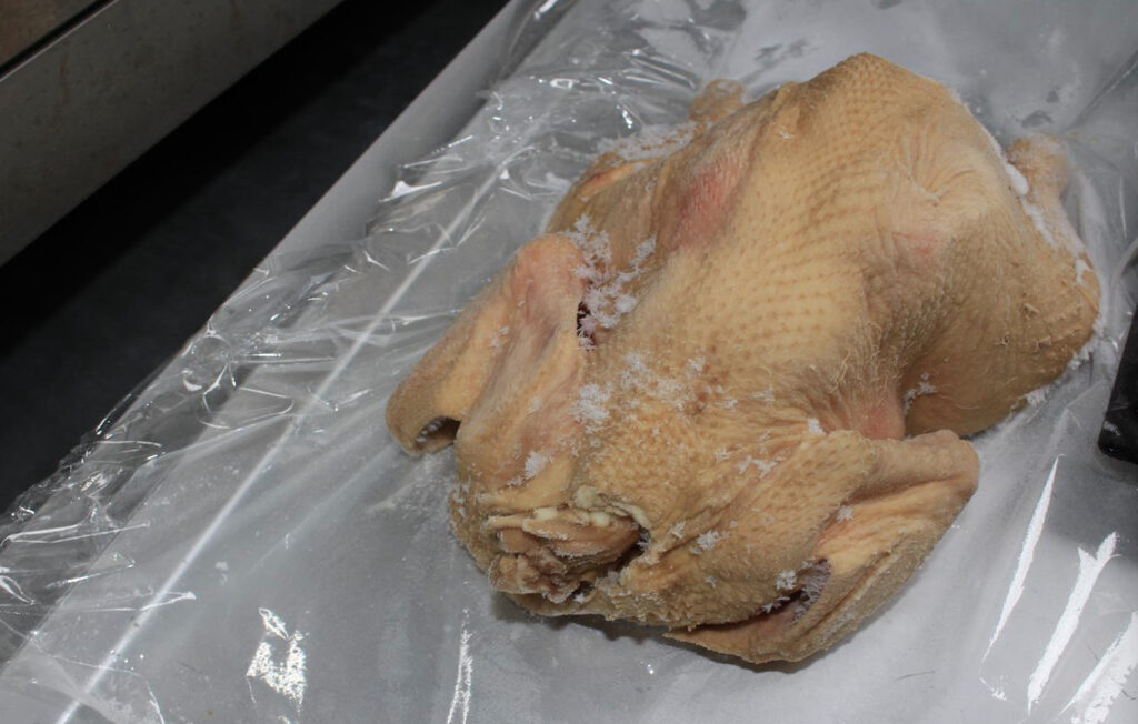 トレイの上にのせられた急速冷凍された丸鶏