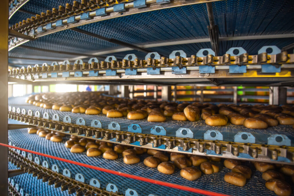 スパイラルフリーザーのネット上にパンが流れている