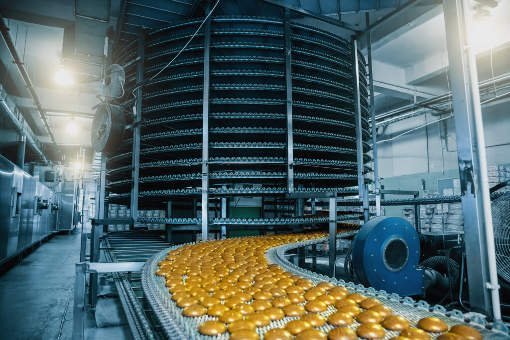 食品がコンベアの上に流れてスパイラルドラムの中に入っていく様子