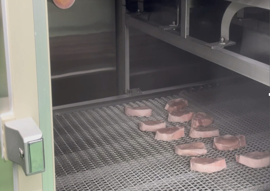 トンネルフリートンネルフリーザーのベルト上に製品が流れているザーのベルト上に製品が流れている