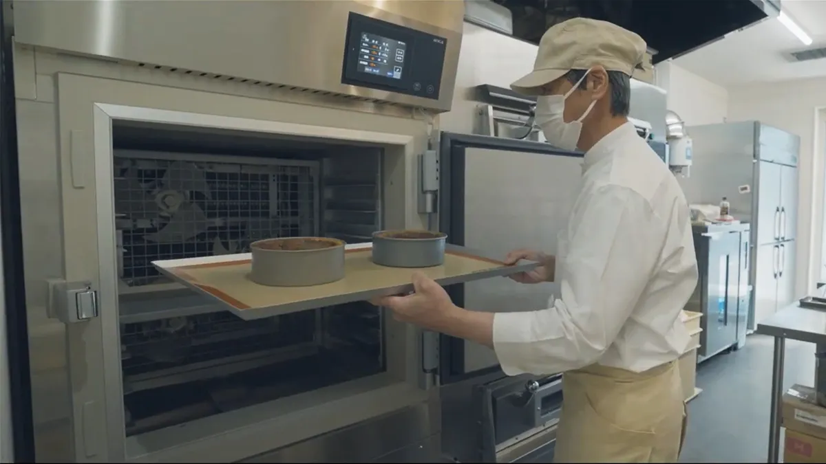 坂本洋菓子店の職人が、焼型を載せた天板を3Dフリーザーへ入れる様子